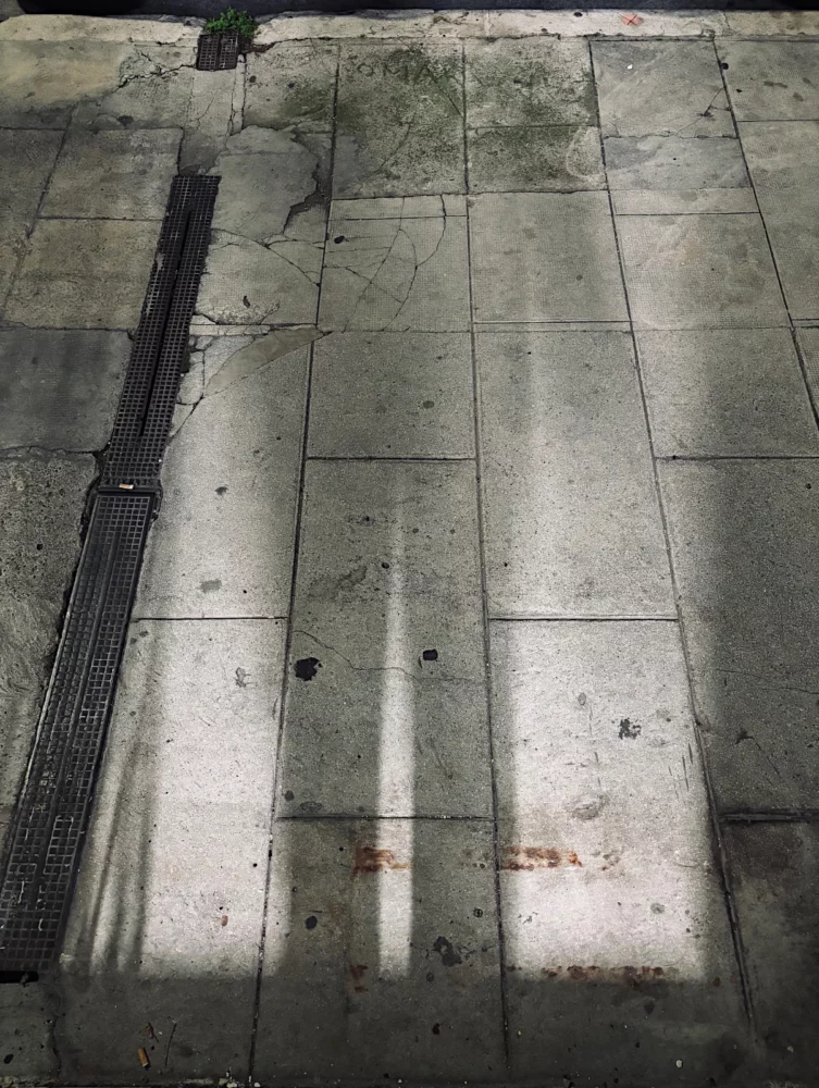 Ombres portées linéaires sur un sol de dalles en pierre sous une lumière rasante